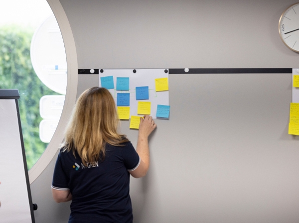 A women sticky a sticky note on a wall